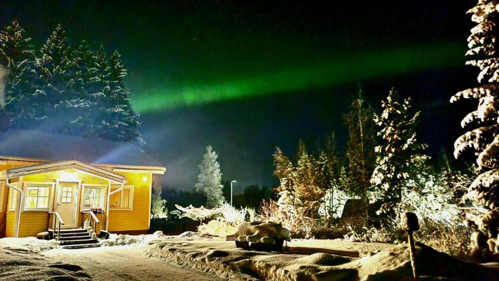 a cabin with a green aurora in the sky at Peaceful house for relaxing in Oulu