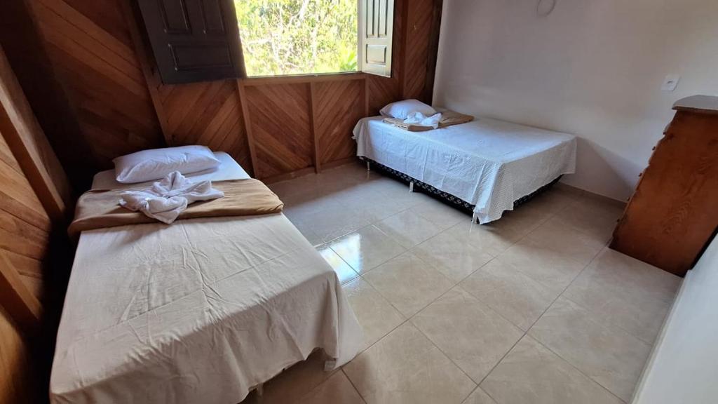 una habitación con dos camas y una ventana en Casa Toca do Tatu, en Manacapuru