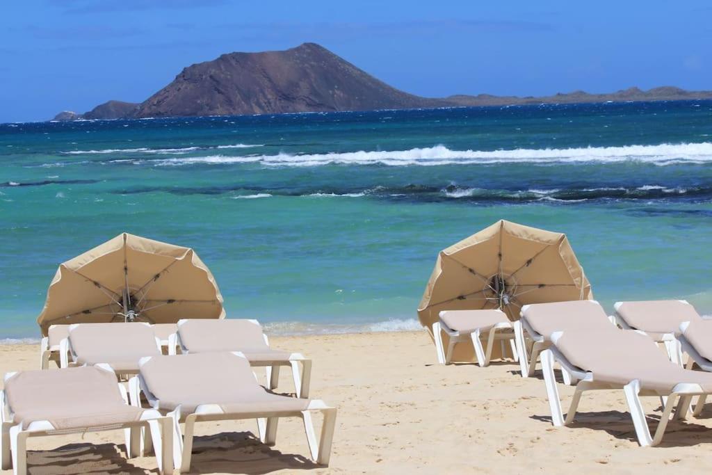 a group of chairs and umbrellas on a beach at Beach Front House 'Casa Neen' in Corralejo