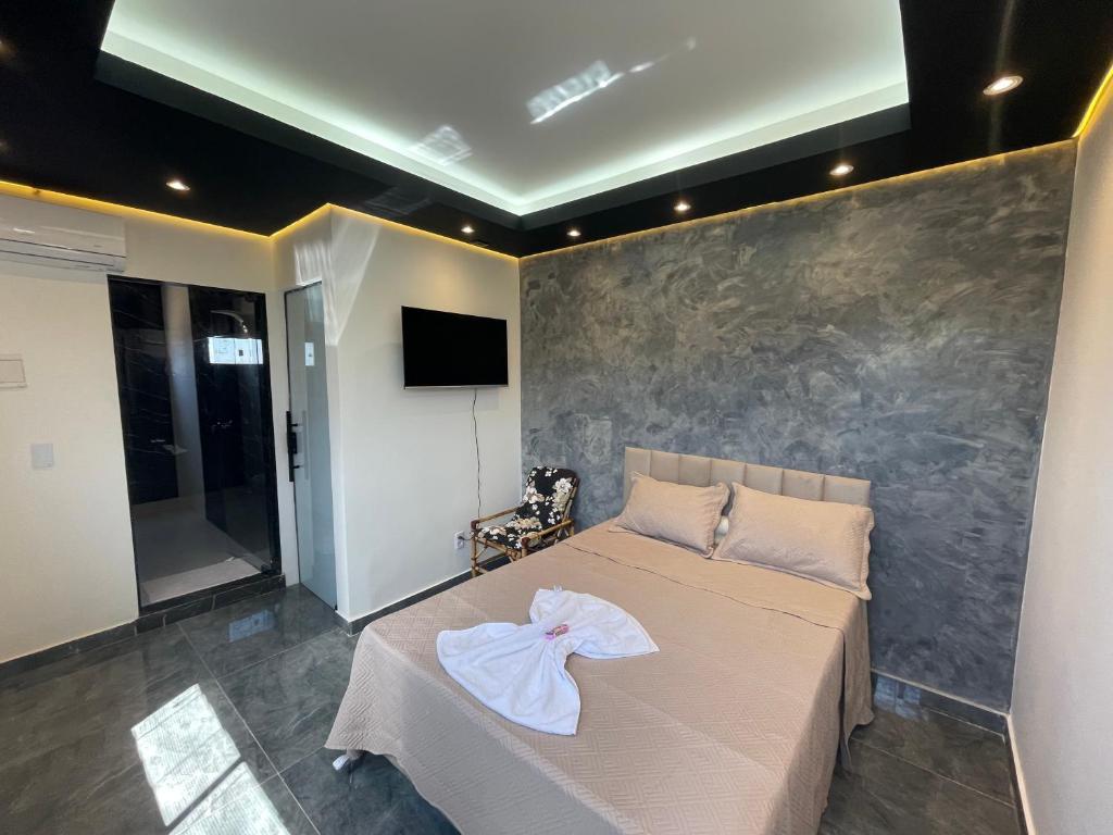 a bedroom with a bed with a robe on it at Suíte Silver 201 com ar condicionado in Santo Antônio do Descoberto