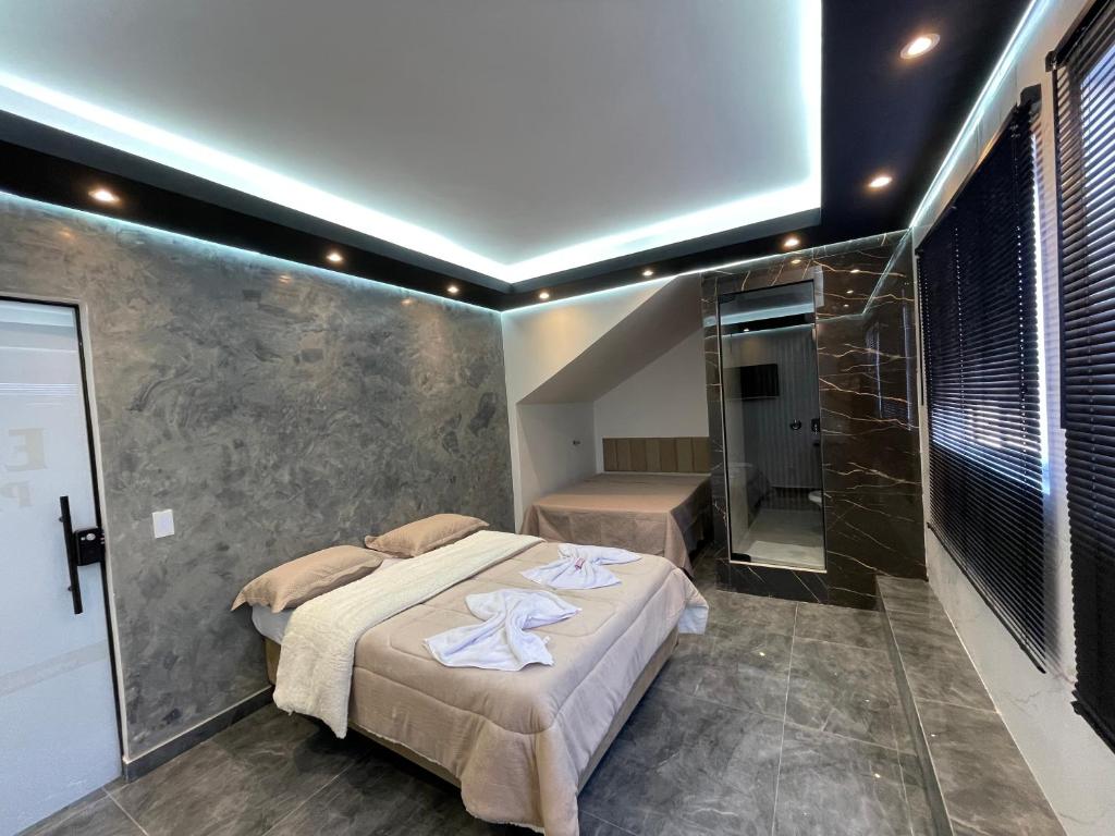 a bedroom with a bed and a walk in shower at Suíte Silver com sofa cama in Santo Antônio do Descoberto