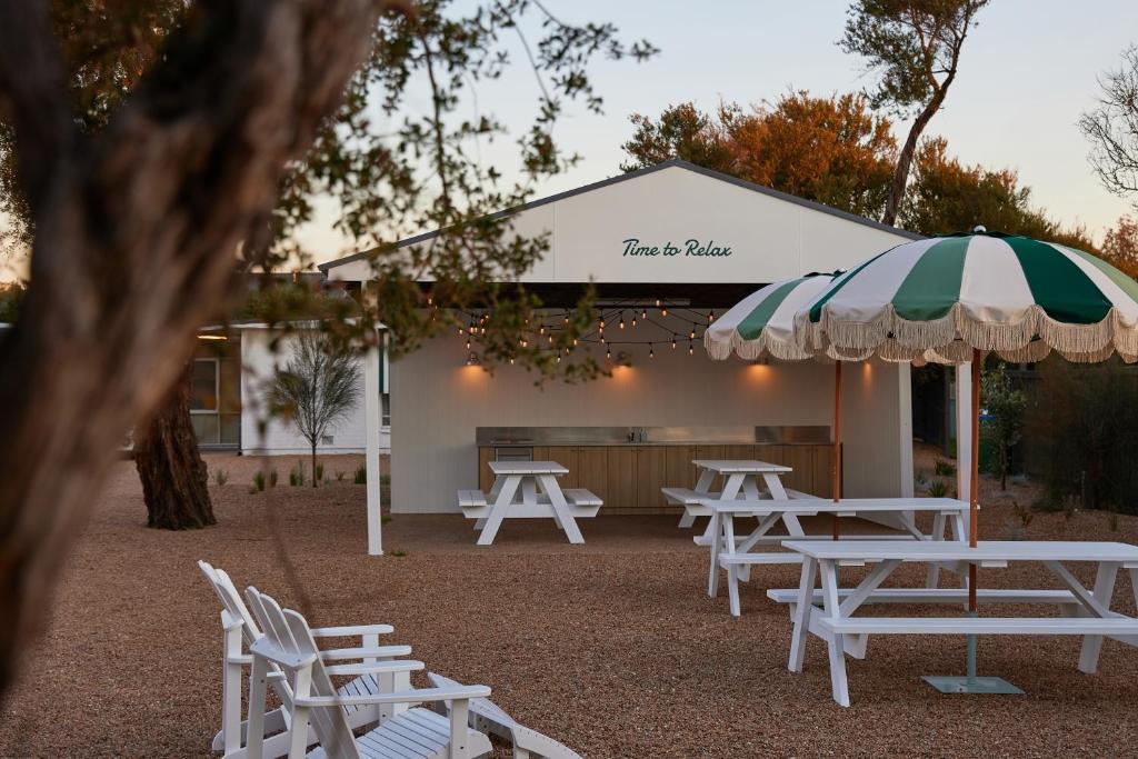 a group of tables and chairs with an umbrella at The Keith Motel in Tootgarook