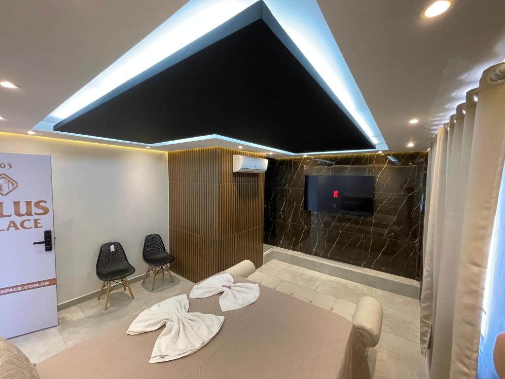 a living room with a large flat screen tv and chairs at Suíte Gold Cinema 303 in Santo Antônio do Descoberto