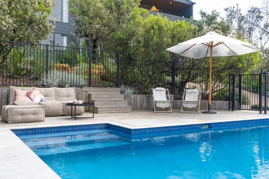 a pool with two chairs and an umbrella next to at The Dreaming in Saint Andrews Beach