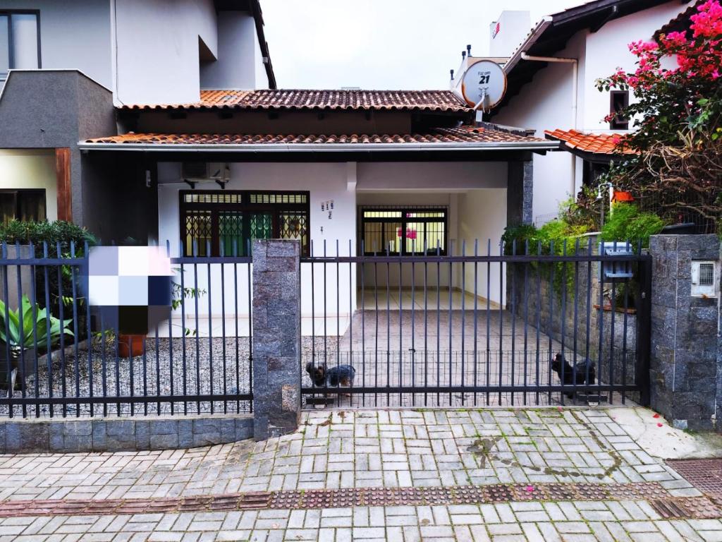 a black fence in front of a house with cats at Linda Casa na Praia de Bombas in Bombinhas