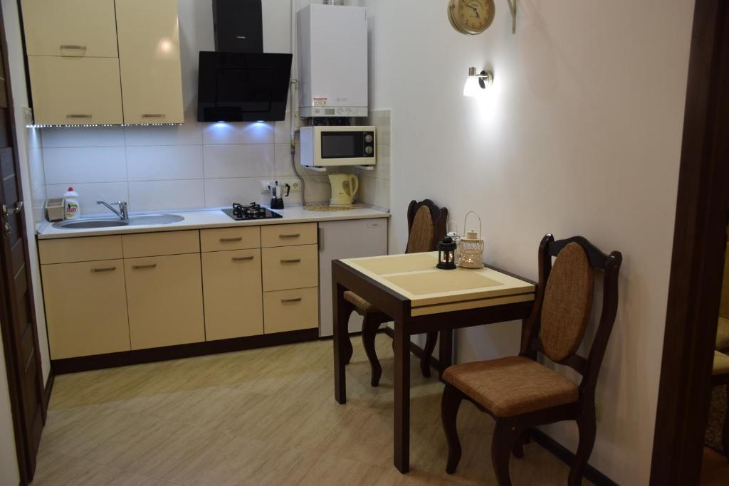 eine Küche mit einem Tisch, Stühlen und einem Waschbecken in der Unterkunft Near Citadel Apartment 2 in Lwiw