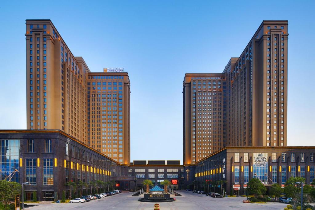 due edifici alti con macchine parcheggiate di fronte di Millennium Hotel Fuqing a Fuqing