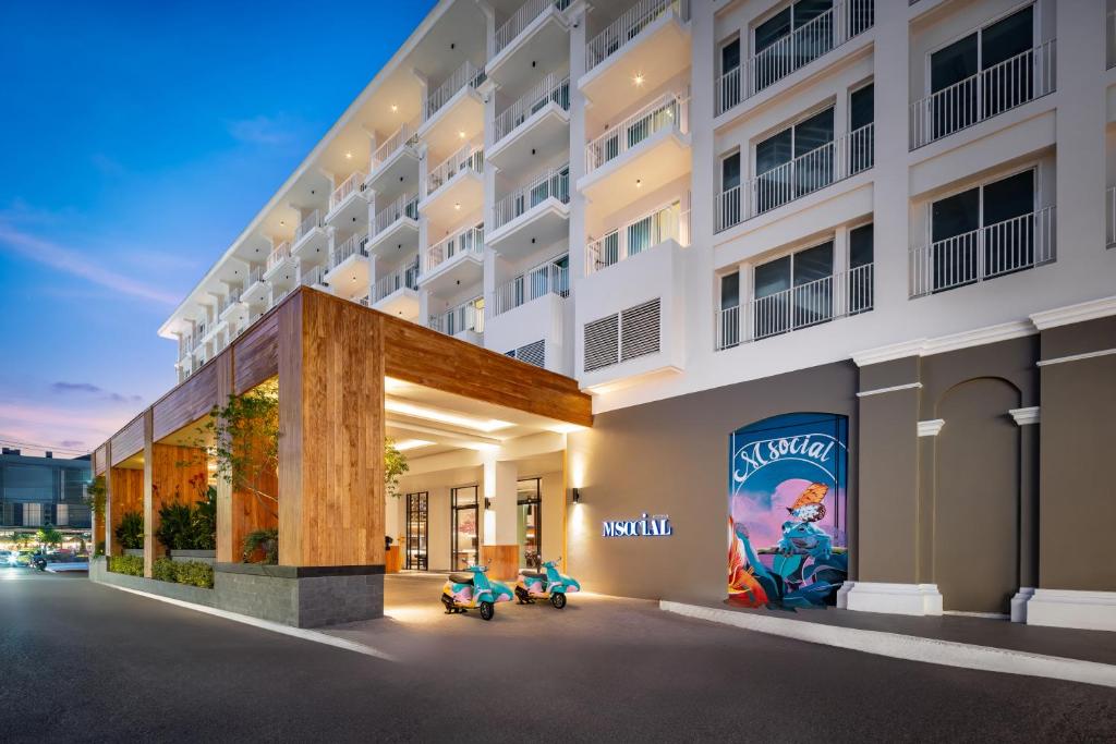 a building with two scooters parked outside of it at M Social Hotel Phuket in Patong Beach