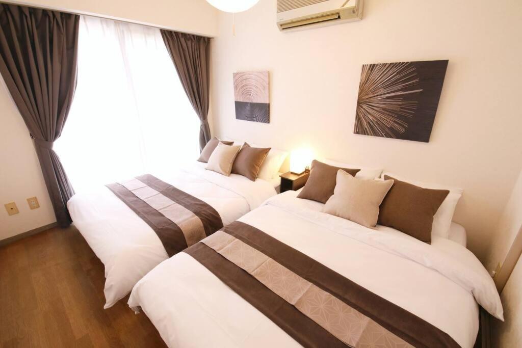 two beds in a hotel room with a window at キャピタルジン熱海202 in Atami