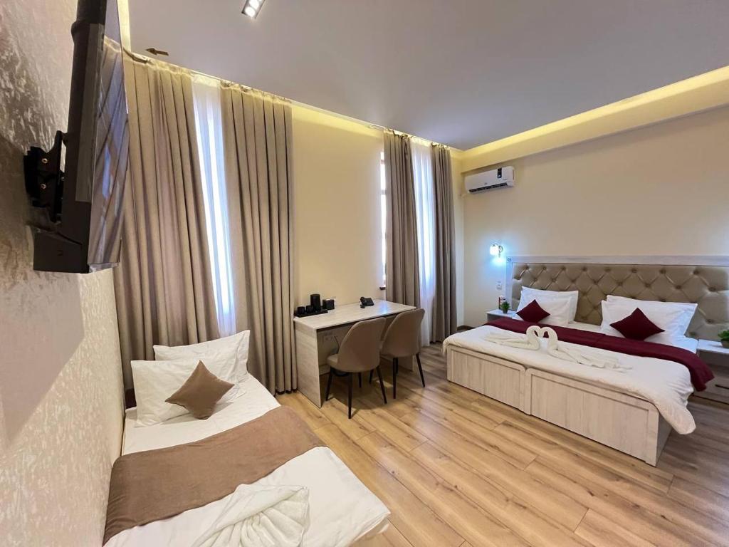 Un dormitorio con dos camas y una mesa y un escritorio. en AKS Hotel, en Tashkent