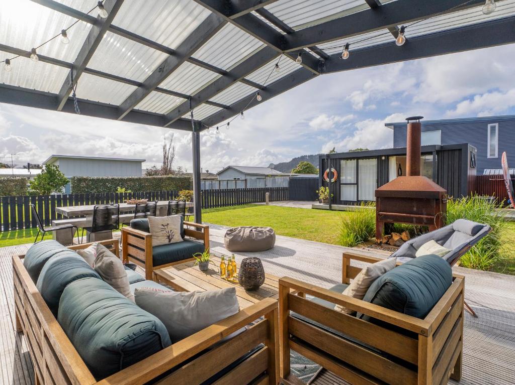un patio con sofá y sillas bajo una pérgola en Sunny Hideaway - Whangamata Holiday Home, en Whangamata