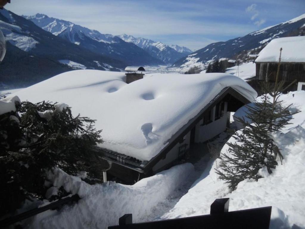 a house covered in snow with mountains in the background at Chalet on the ski slope in Dorf