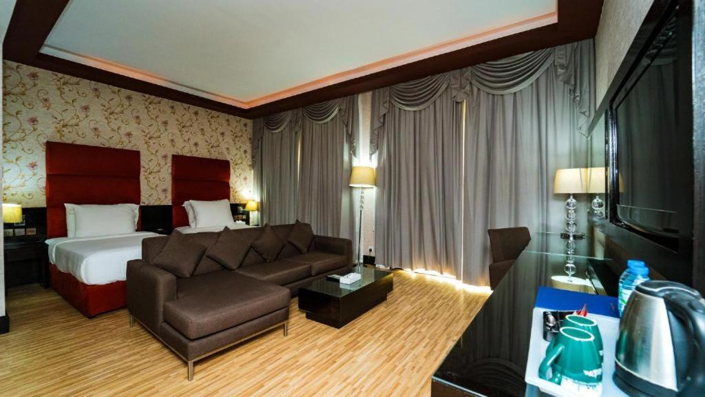 a hotel room with a couch and a bed at Mangrove Hotel in Ras al Khaimah