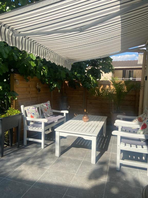 un patio avec deux chaises, une table et un parasol dans l'établissement Maison Parking-10 min Aéroport, à Orly
