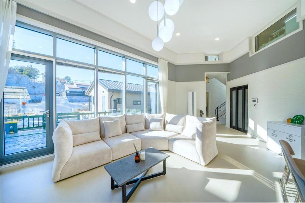 a living room with a white couch and large windows at Gangneung Uahaeng Stay Private House in Gangneung