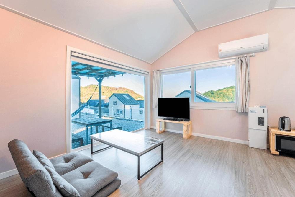 a living room with a couch and a television at Gangneung Dawon Hill Pension in Gangneung
