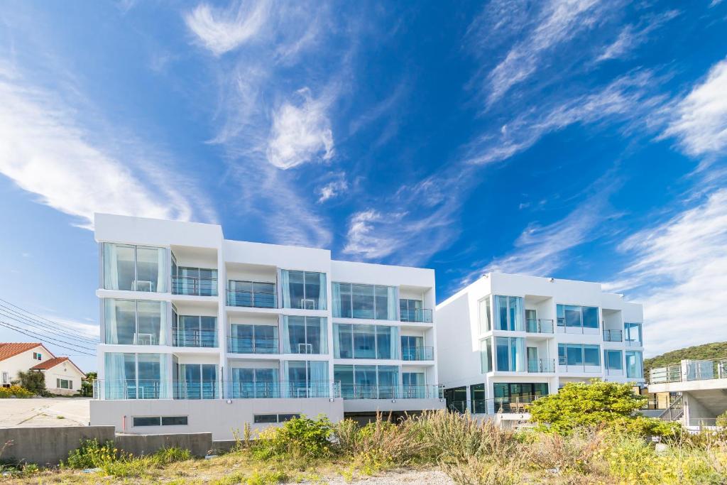 een wit appartementencomplex met een blauwe lucht bij Geoje Hill Point Youth Hostel in Geoje 