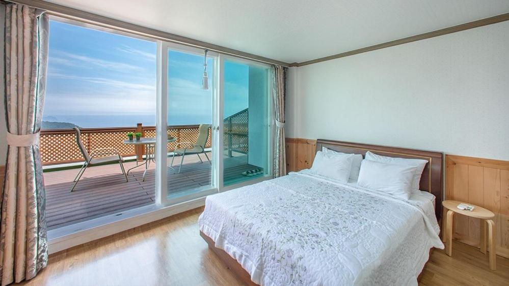 a bedroom with a bed and a balcony with a view at Samcheok Donghae Raeyo Pension in Samcheok