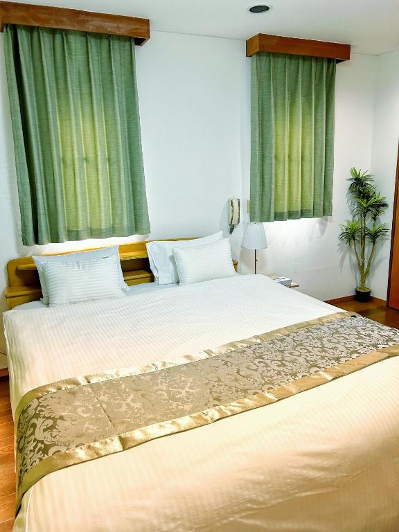 a bedroom with a large bed with green curtains at Uhome Ueno Hotel in Tokyo
