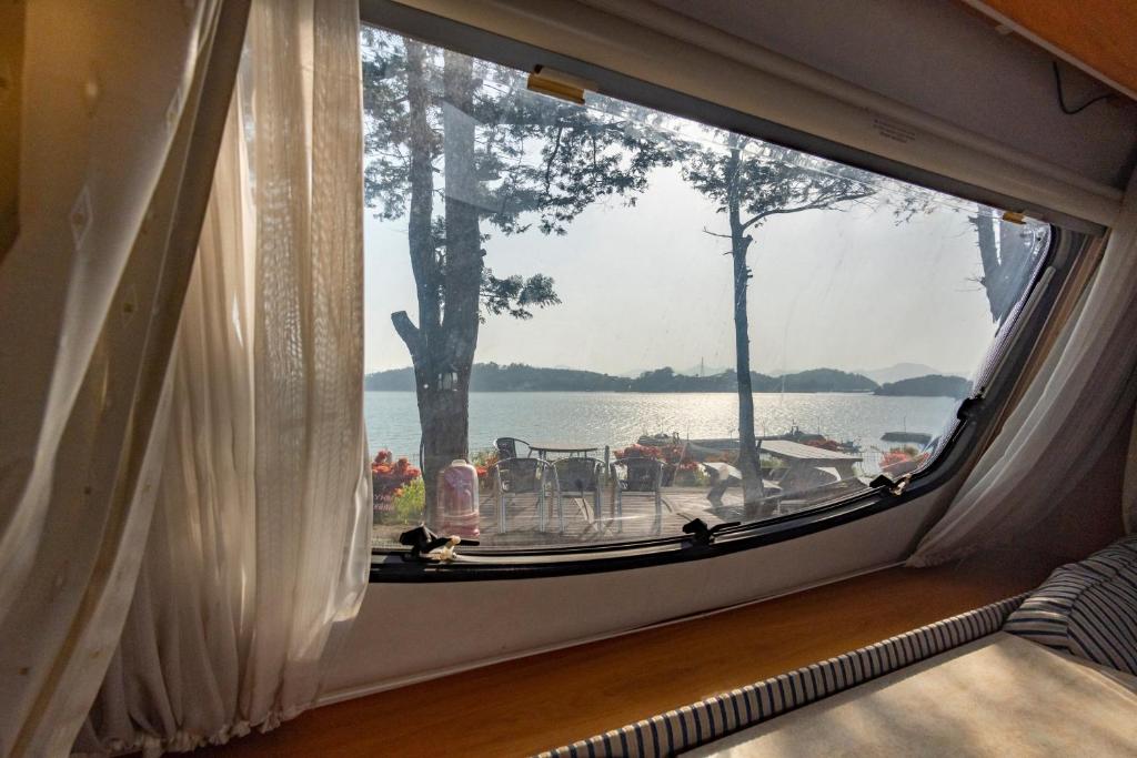 una finestra in una camera con vista sul lago di Yeosu Gyeongdo Pension a Yeosu