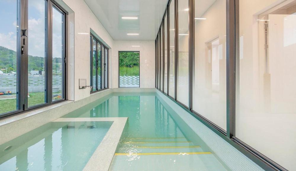 a swimming pool in a building with windows at Yeosu Pyeongsari 85-7 Kids Pool Villa in Yeosu