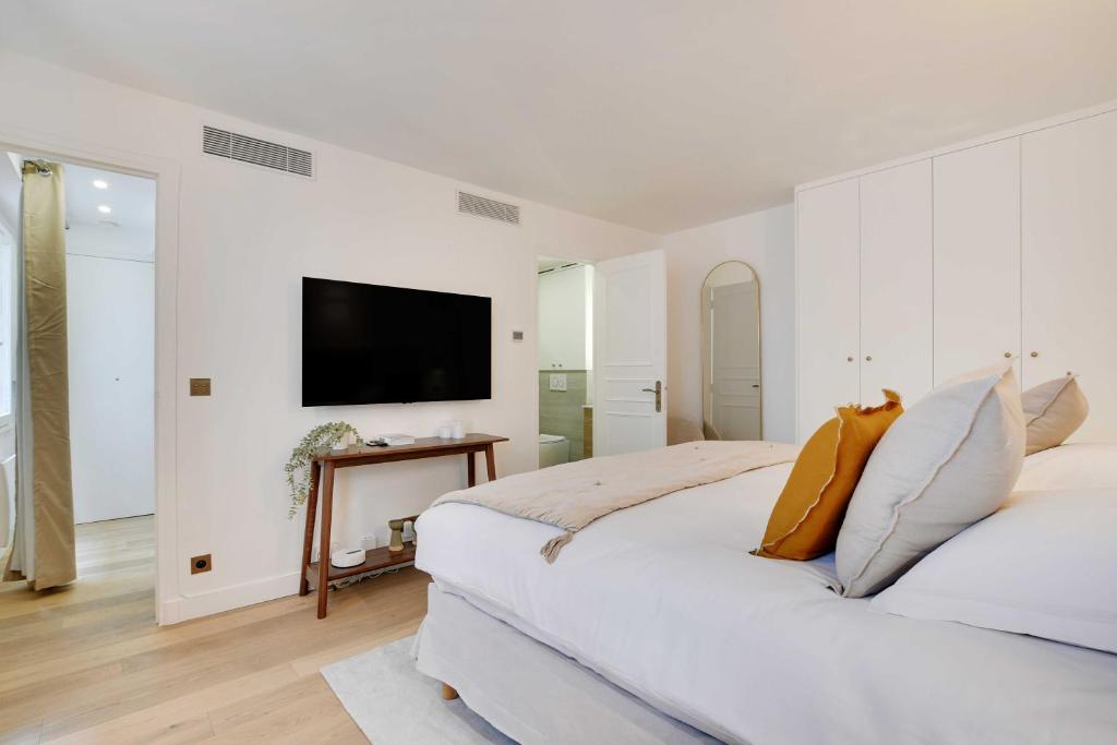 une chambre blanche avec un grand lit et une télévision à écran plat dans l'établissement Superb apartment with AC - 1BR-2P - Arts et Métier, à Paris
