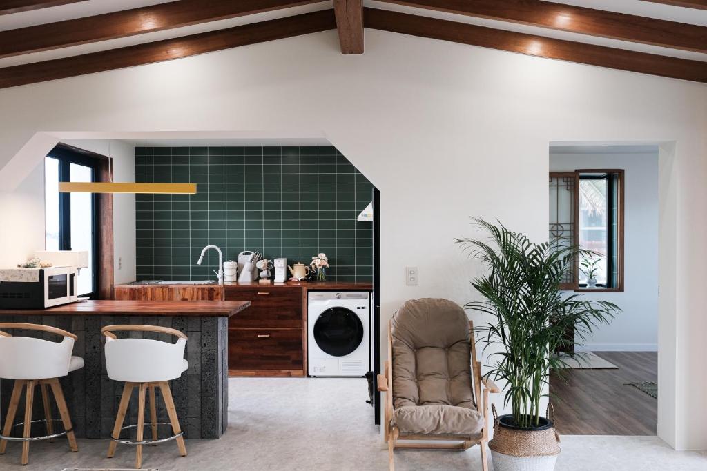 a kitchen with a counter and a green tile wall at Stay Hyeopjae Soop in Jeju