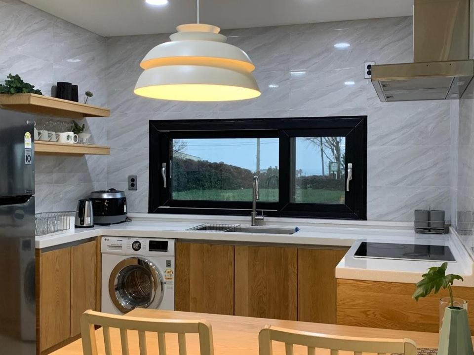una cocina con fregadero y ventana en Jeju Ianstay, en Jeju