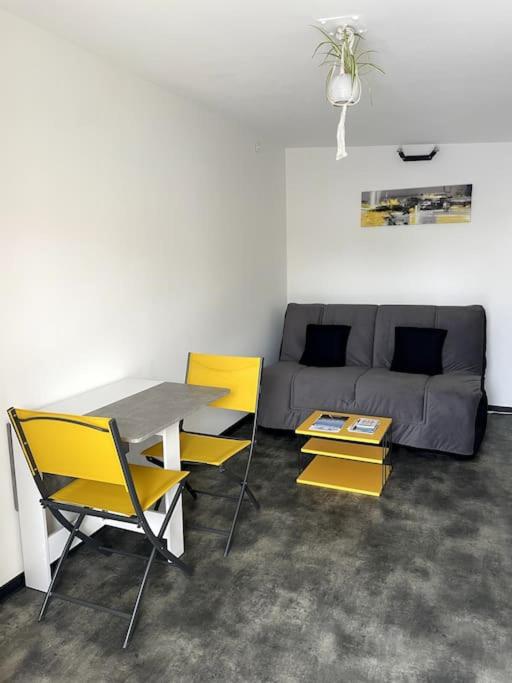 un salon avec une table et des chaises jaunes dans l'établissement Studio de 25m carré refait à neuf, proche tram B et fac, à Pessac
