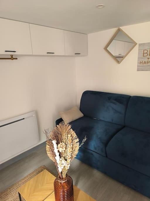 - un salon avec un canapé bleu et un vase fleuri dans l'établissement Studio moderne situé à 300m du cœur de Troyes, à Troyes