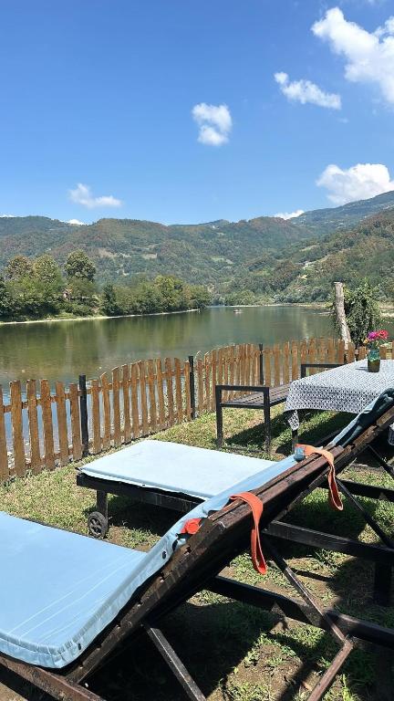 a picnic table next to a lake next to a fence at Vukova Brvnara in Drlače