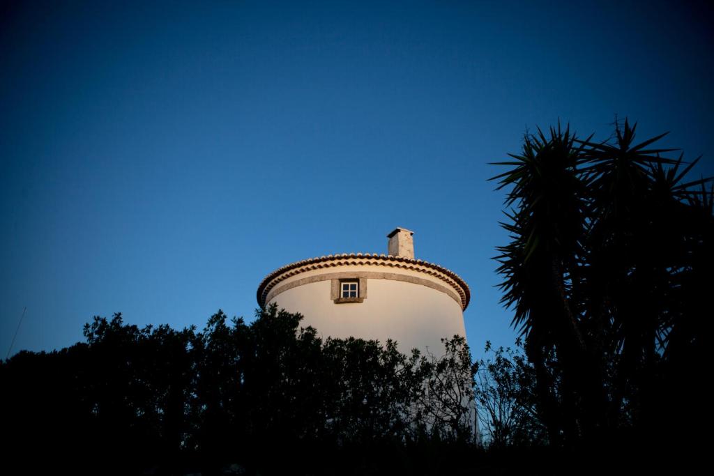 a tower with a tree in front of a blue sky at Ha Mar ao Luar in Setúbal