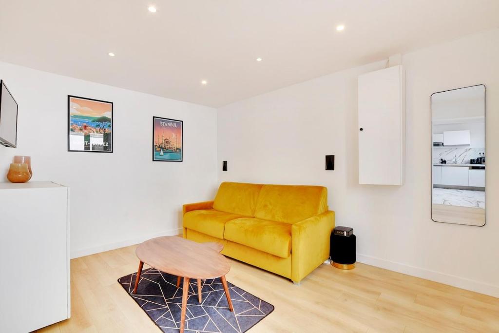 un salon avec un canapé jaune et une table dans l'établissement Cosy au Parc des Buttes Chaumont, à Paris