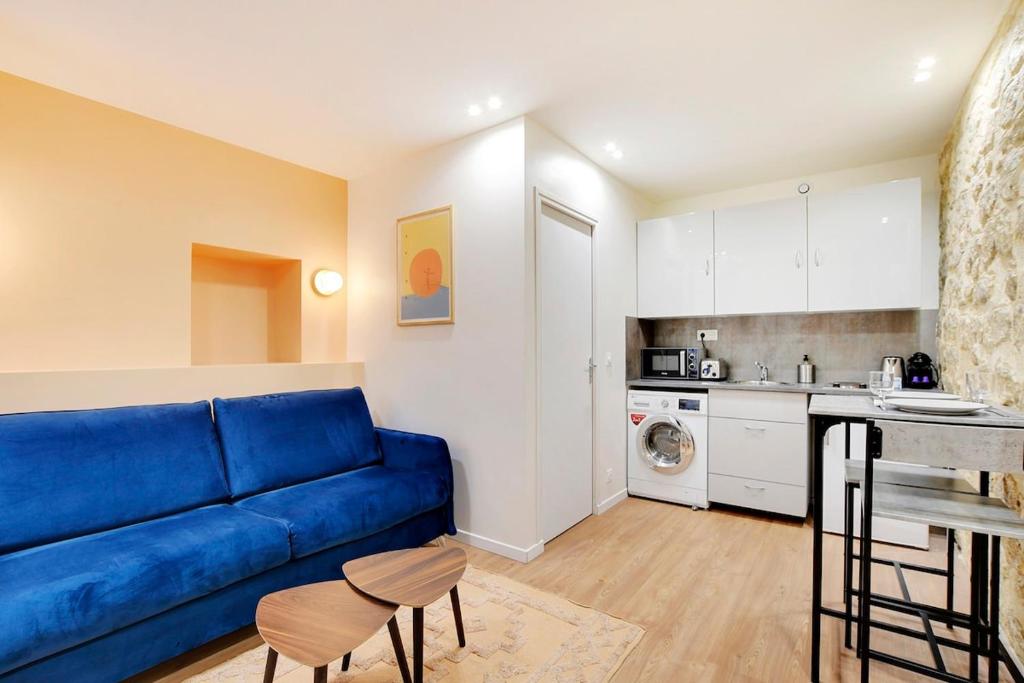 un salon avec un canapé bleu et une cuisine dans l'établissement Appartement neuf au coeur de Paris, à Paris