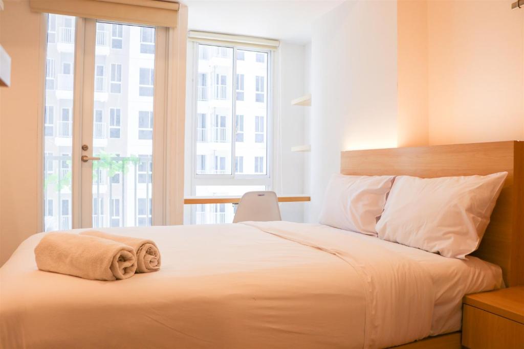 ein Schlafzimmer mit einem weißen Bett mit einem großen Fenster in der Unterkunft Modern Studio Room at Tokyo Riverside PIK 2 Apartment By Travelio in Rawalembang