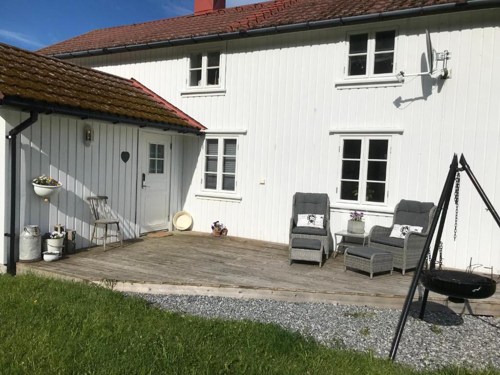 una casa blanca con un patio de madera con dos sillas en Restaurert Nordlandshus, en Brønnøysund