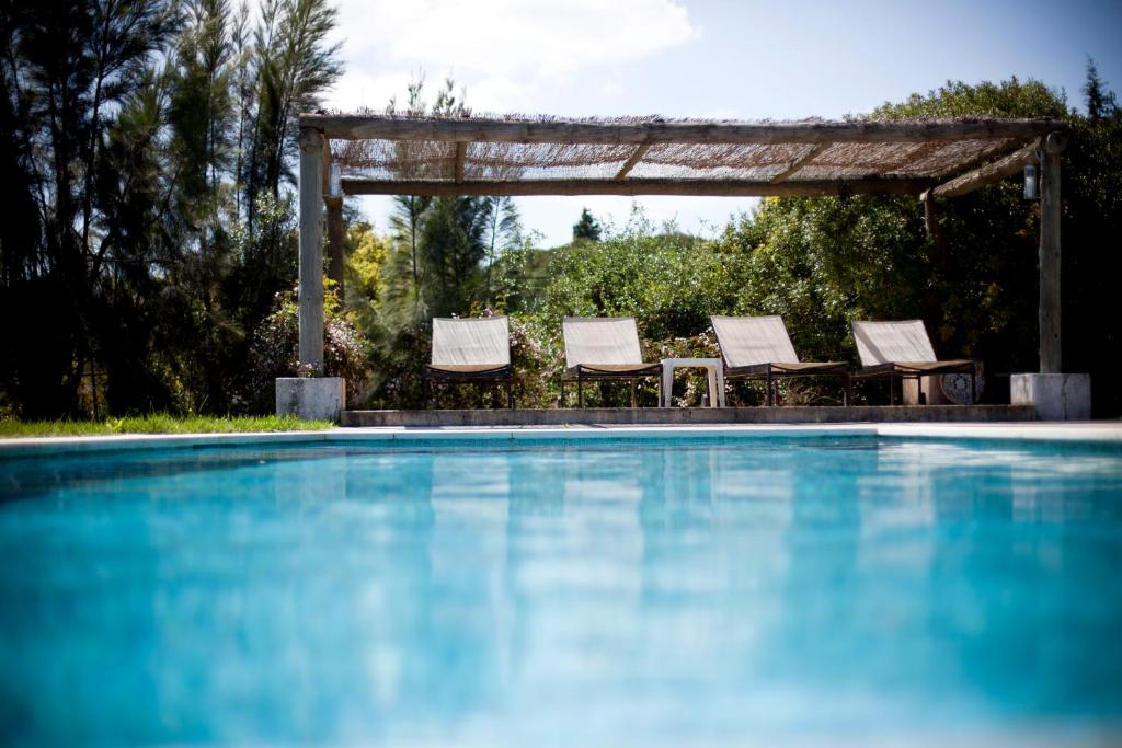 a swimming pool with chairs and a gazebo at Ha Mar ao Luar in Setúbal