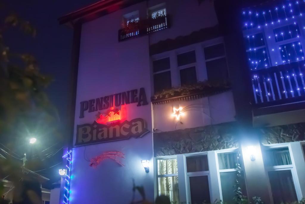 a building with a sign on the side of it at night at Pensiunea Bianca in Botoşani