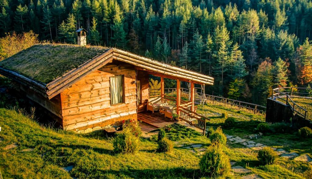 una cabaña de madera en una colina en un bosque en Панорама хаус Лещен и еко къщи Дървена и Землянка, en Leshten