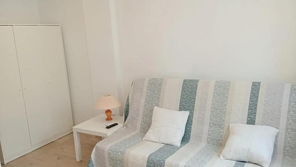 a couch with two pillows sitting next to a table at Charming apartment in La Ràpita, 30 m² with balcony in Sant Carles de la Ràpita