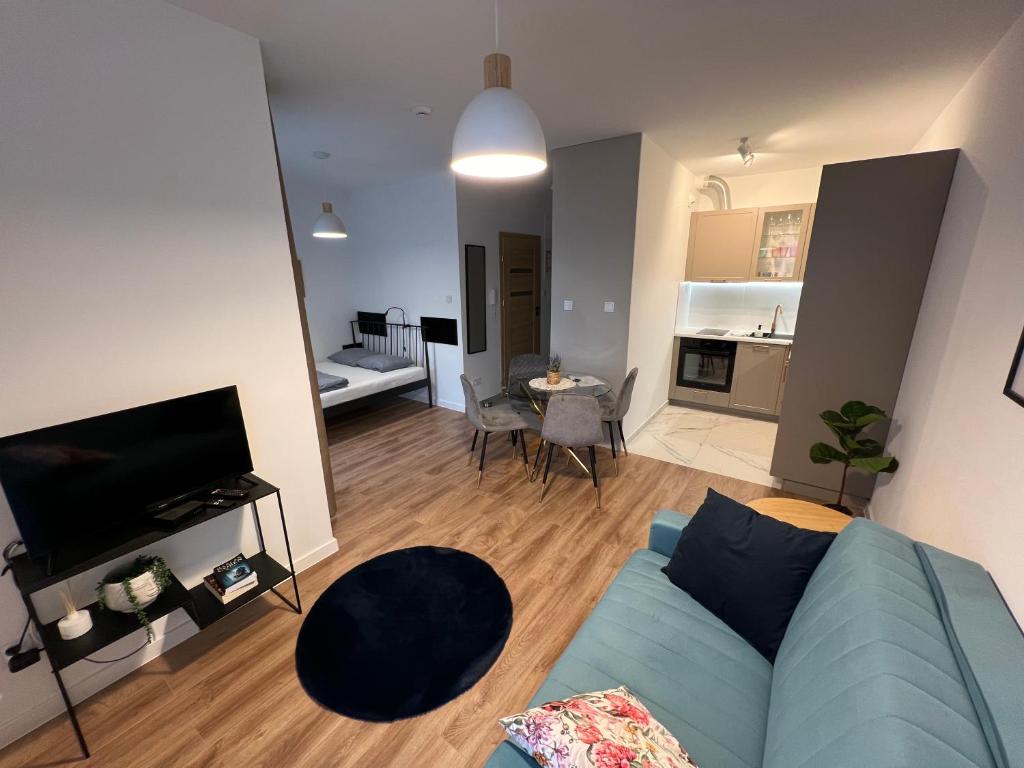 a living room with a blue couch and a kitchen at Mikołowska Small Heaven - free underground parking in Katowice