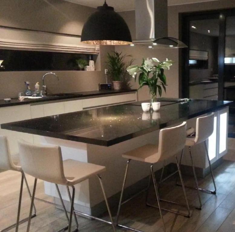 a kitchen with a large island with white bar stools at Rom til leie - rolig villastrøk nært flyplassen in Tromsø