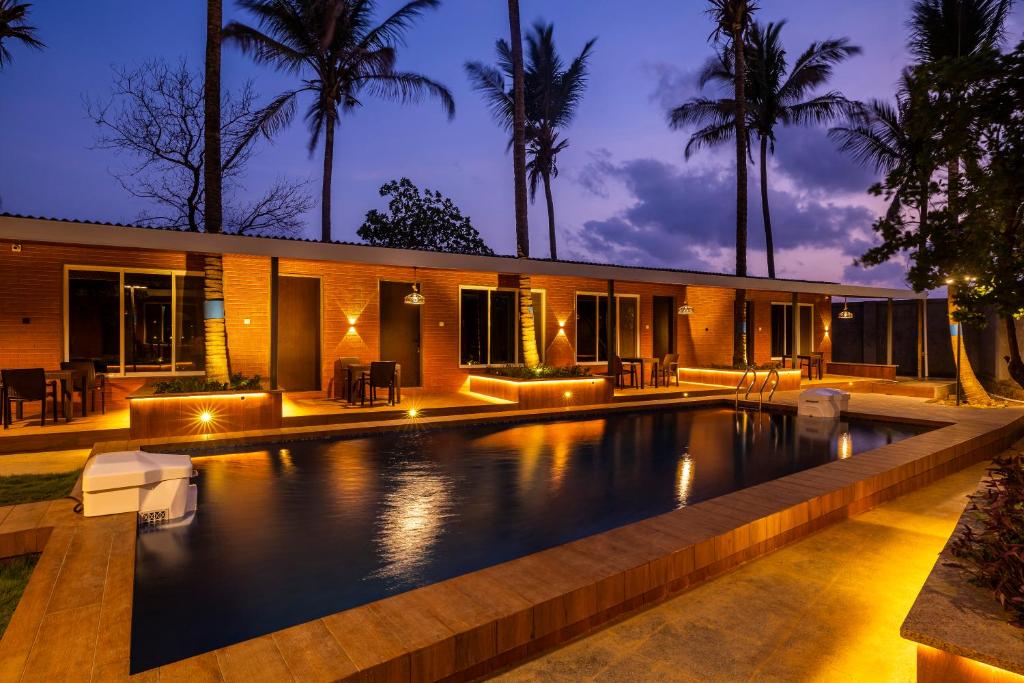 an infinity pool in front of a house with palm trees at Coco Bliss By Mauli Stays in Manor