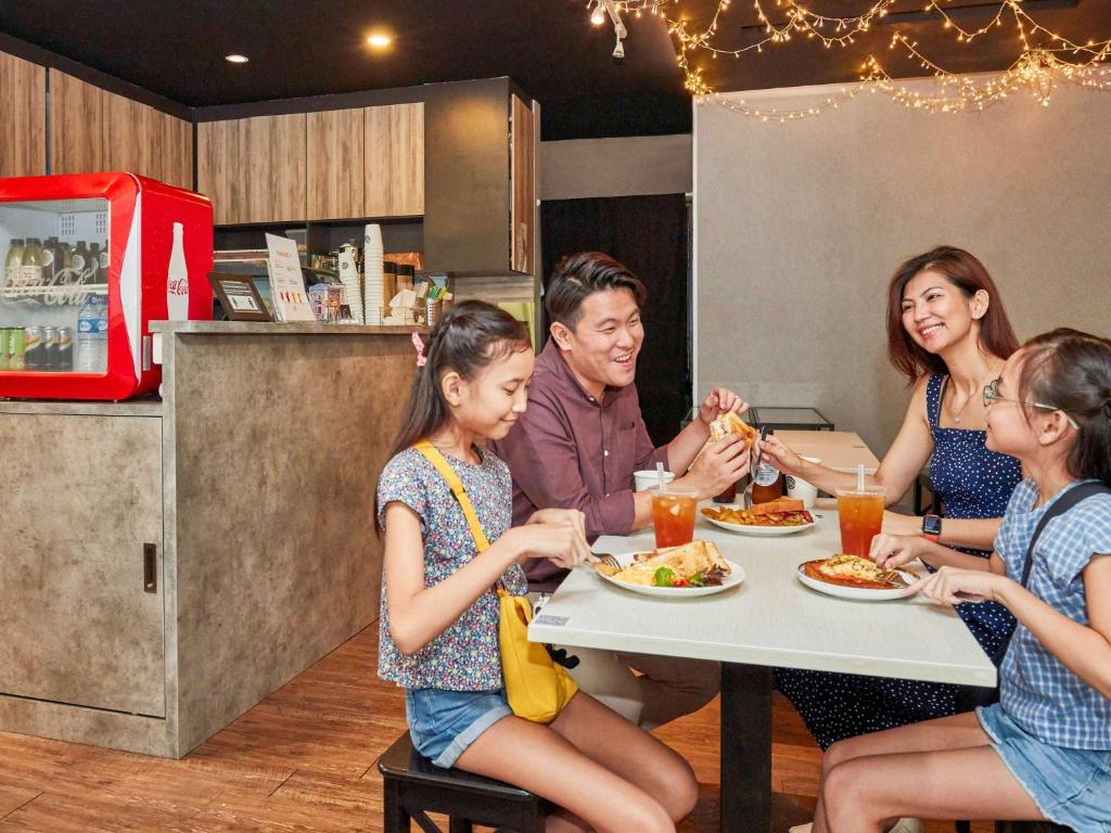 a group of people sitting at a table eating food at ibis budget Singapore Clarke Quay in Singapore