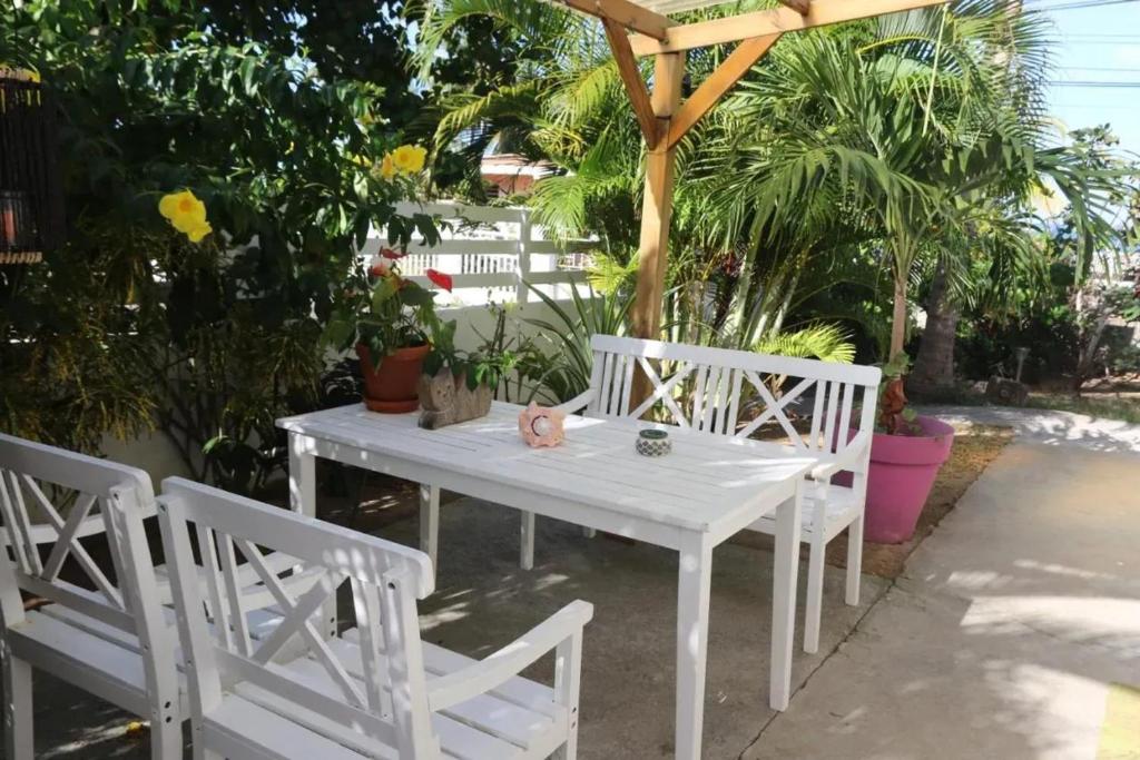 a white table and chairs under a wooden umbrella at Charmant studio à La Trinité 30 m² avec jardin privé in La Trinité