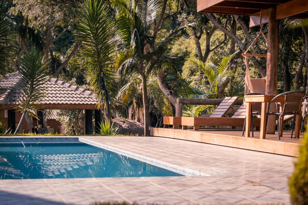 una piscina con un banco y una silla al lado en Chalés Villa Pinhal - Hidromassagem dupla, lareira e café da manhã - 12 km do centro, en Santo Antônio do Pinhal
