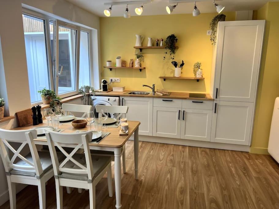 eine Küche mit einem Holztisch und weißen Schränken in der Unterkunft Appart cosy, calme proche centre in Caen