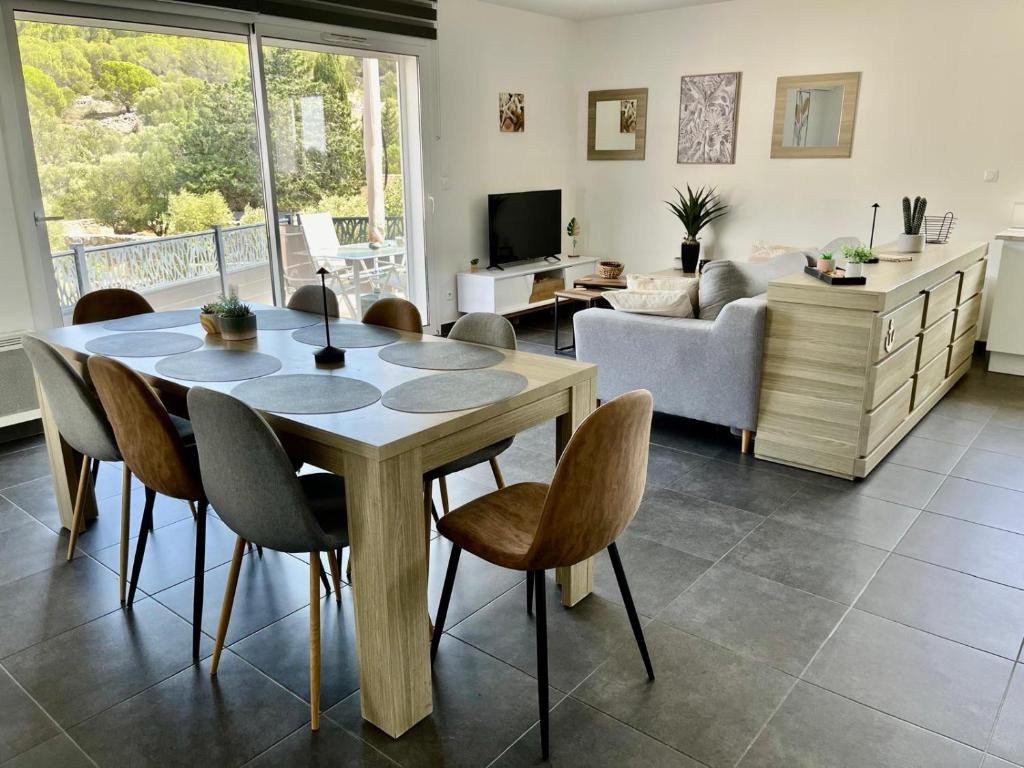 un salon avec une table et des chaises en bois dans l'établissement Charmante maison vue garrigue avec piscine, à Lapalme