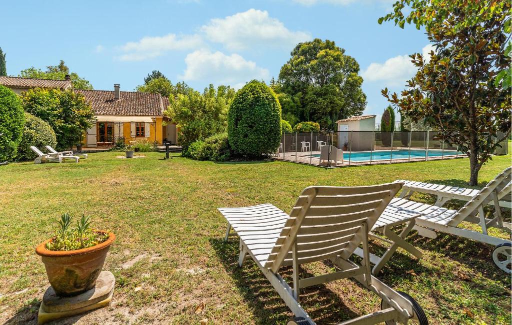 une cour avec deux bancs blancs et une maison dans l'établissement Cozy Home In Pernes Les Fontaines, à Pernes-les-Fontaines
