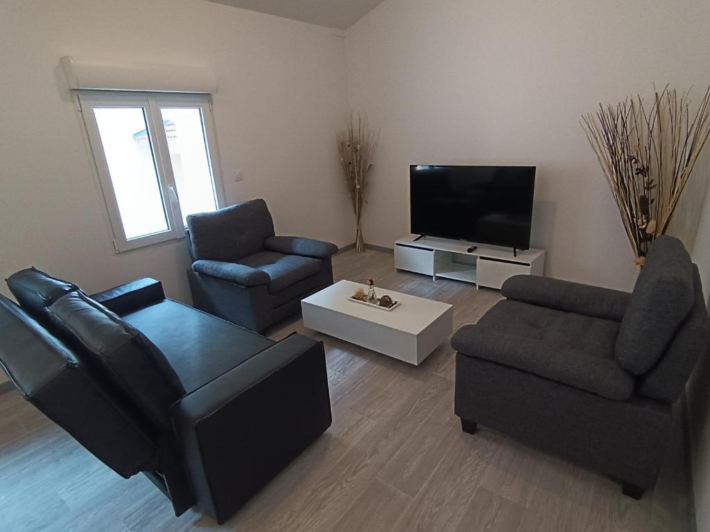 - un salon avec deux chaises et une télévision à écran plat dans l'établissement Appart complet 3 chambres calme facture et repas possibles, à Beausemblant